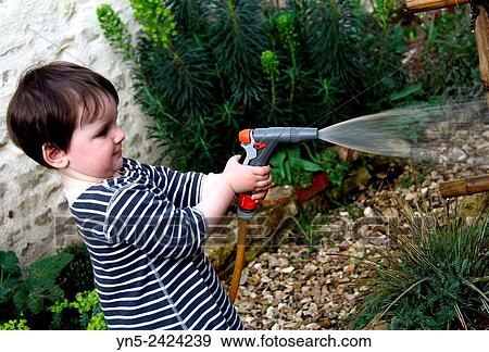 Child watering a garden View Large Photo Image Stock Photo - Child watering a garden. Fotosearch