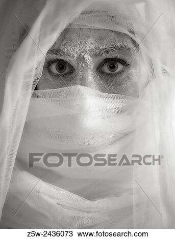 Stock Image - Close up woman eyes and ashes, she wearing white canvas, tinted black and white image, intentional noise added.. Fotosearch