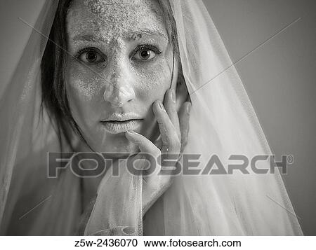 Stock Image - Close up woman face and ashes, she wearing white canvas, tinted black and white image, intentional noise added.. Fotosearch