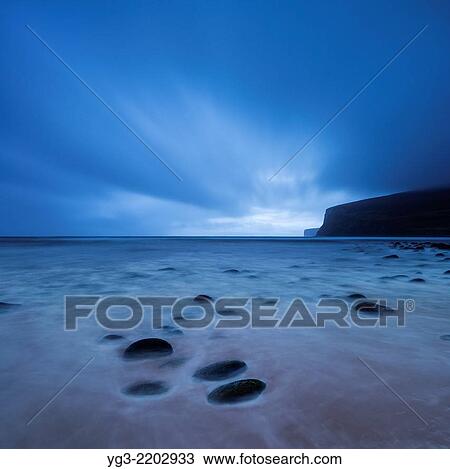 Stock Image - Clouds sweep across sky in fading light over beach at Rackwick Bay, Hoy, Orkney, Scotland.. Fotosearch