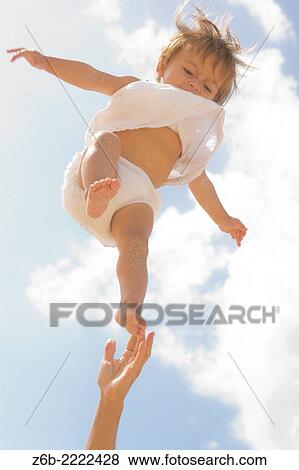 Stock Photo - Eleven months old baby girl being hold by her father.. Fotosearch
