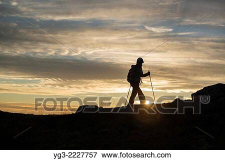 Stock Photo - Female hiker hiking in Evening summer sun on summit of Ryten, Moskenesoy, Lofoten Islands, Norway.. Fotosearch