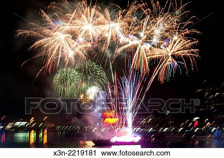 Stock Image - Fireworks Shooting off a barge during New Years Eve celebration at Baltimore´s Inner Harbor with the Domino Sugar sign in the horizon. The location is Baltimore, Maryland, USA.. Fotosearch