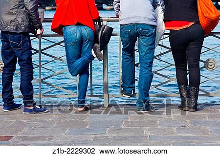 Stock Image - Four people leaning on a railing in Geneva, Switzerland.. Fotosearch