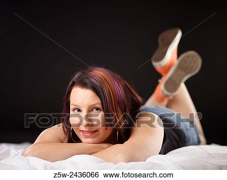 Stock Photograph - Girl on Bed in Converse Sneakers.. Fotosearch