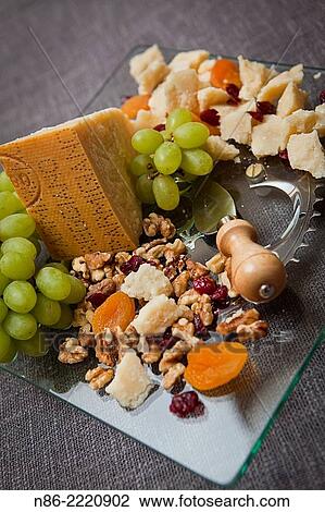 Stock Image - glass serving tray with assortment of fruits nuts and parmesan cheese.. Fotosearch