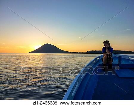 Gril at boat looking at volcano Manado Tua at sunset in Manado, Sulawesi, Indonesia View Large Photo Image Stock Photography - Gril at boat looking at volcano Manado Tua at sunset in Manado, Sulawesi, Indonesia. Fotosearch