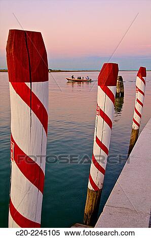 Stock Photography - Laguna at sunset with red and white Paline, mooring posts, Venice, Italy.. Fotosearch