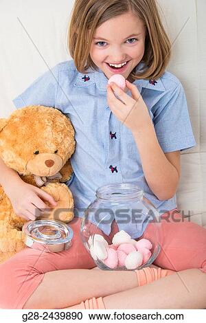 Little girl eating sweets and cuddling her teddy bear View Large Photo Image Stock Image - Little girl eating sweets and cuddling her teddy bear. Fotosearch