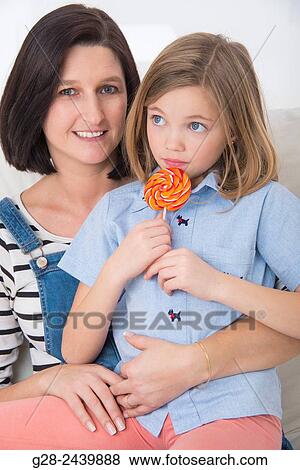 little girl sitting on her mother´s lap and licking a colored lollipop View Large Photo Image Stock Photo - little girl sitting on her mother´s lap and licking a colored lollipop. Fotosearch