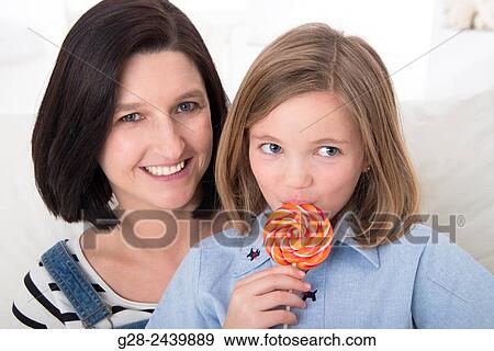 little girl sitting on her mother´s lap and licking a colored lollipop View Large Photo Image Stock Photo - little girl sitting on her mother´s lap and licking a colored lollipop. Fotosearch