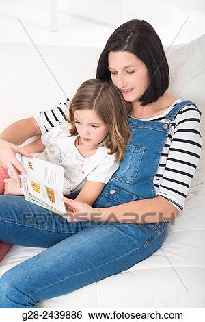 Little girl sitting on her mother's lap, and reading a book in her bedroom View Large Photo Image Stock Photograph - Little girl sitting on her mother's lap, and reading a book in her bedroom. Fotosearch