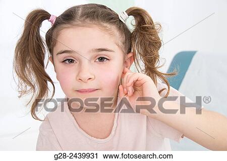 Little girl with bunches stopping her ear with her finger sitting on a medical couch View Large Photo Image Stock Image - Little girl with bunches stopping her ear with her finger sitting on a medical couch. Fotosearch