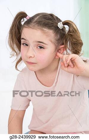 Little girl with bunches stopping her ear with her finger sitting on a medical couch View Large Photo Image Stock Photo - Little girl with bunches stopping her ear with her finger sitting on a medical couch. Fotosearch
