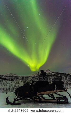 Stock Photo - Man on snowmobile watching Northern light in Riksgränsen, Kiruna, Swedish lapland.. Fotosearch