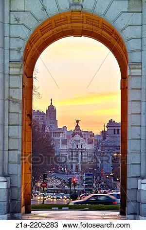 Stock Image - Metropolis building seen through Puerta de Alcala monument by sunset. Madrid, Spain.. Fotosearch