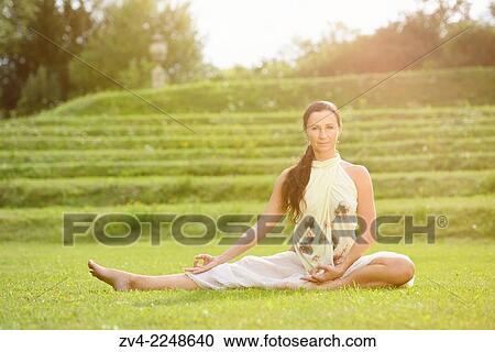 Stock Image - Middle aged woman doing yoga in a park in summer, Germany.. Fotosearch