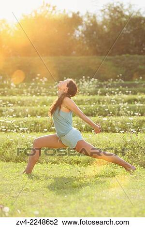 Stock Image - Middle aged woman doing yoga in a park in summer, Germany.. Fotosearch
