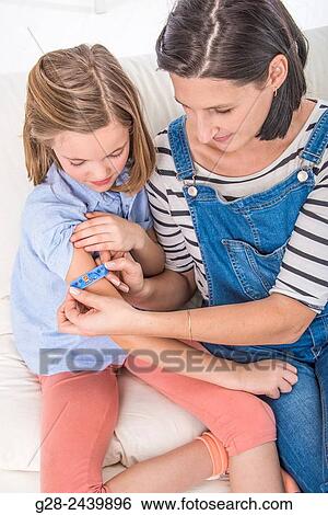 Mother putting a clean dressing on the arm of her daughter View Large Photo Image Stock Photograph - Mother putting a clean dressing on the arm of her daughter. Fotosearch