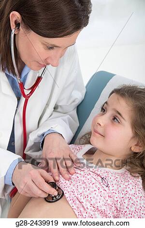 Stock Photo - Paediatrcian doctor examining little girl lying on medical couch, with her stethoscope. Fotosearch