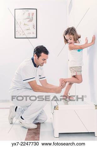 Stock Image - Podologist treating a young girl.. Fotosearch