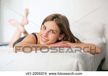 Pretty young woman smiling lying in bed View Large Photo Image Picture - Pretty young woman smiling lying in bed. Fotosearch