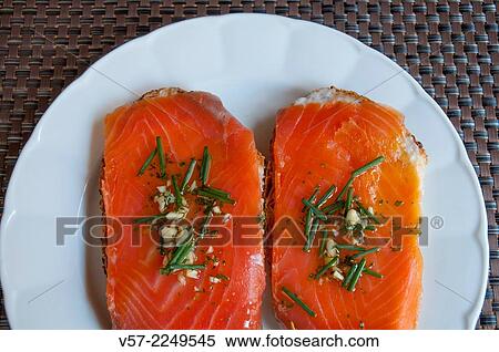 Stock Photography - Smoked salmon with garlic, chives and olive oil on toast.. Fotosearch