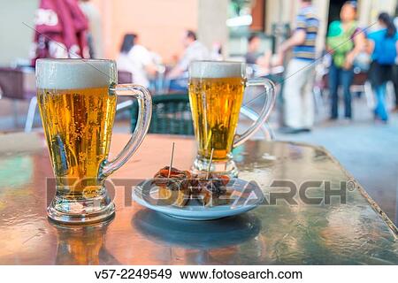 Spanish aperitif: two glasses of beer with a tapa on a terrace. Madrid, Spain. View Large Photo Image Stock Photo - Spanish aperitif: two glasses of beer with a tapa on a terrace. Madrid, Spain.. Fotosearch