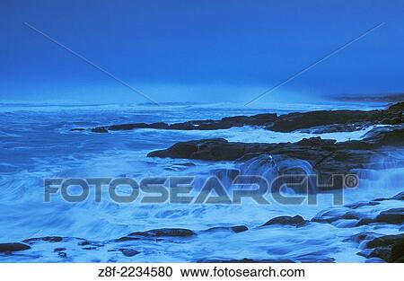 Stock Image - Storm surf hitting rocky coastline at dusk; Yachats Wayside State Park, Oregon.. Fotosearch