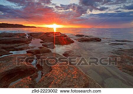Stock Image - Sunset over Georgia Strait from beach in north Nanaimo, Vancouver Island, British Columbia.. Fotosearch