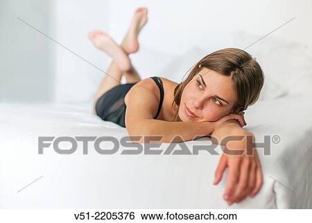 Stock Photograph - Thoughtful young woman lying in bed. Fotosearch