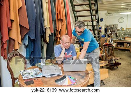 Tilburg, Netherlands. Josef and Werner are apprentice upholsterer and his male partner, both looking at an Apple´s notebook, viewing their newly made images. View Large Photo Image Stock Photo - Tilburg, Netherlands. Josef and Werner are apprentice upholsterer and his male partner, both looking at an Apple´s notebook, viewing their newly made images.. Fotosearch