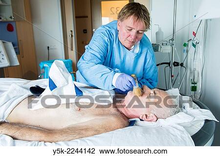 Tilburg, Netherlands. Male orthopedic patient, recovering in a hospital sand bed to prevent decubitus, is nursed by a female nurse, wearing protective clothing against bacterial infection. View Large Photo Image Stock Image - Tilburg, Netherlands. Male orthopedic patient, recovering in a hospital sand bed to prevent decubitus, is nursed by a female nurse, wearing protective clothing against bacterial infection.. Fotosearch