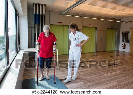 Stock Photo - Tilburg, Netherlands. Physio therapist instructing a female post operative patient on how to walk again, after reviving a new hip in surgery.. Fotosearch