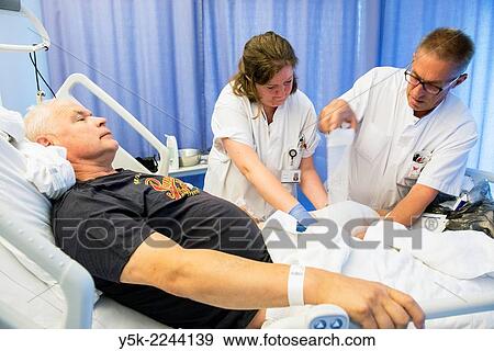Tilburg, Netherlands. Two colleague nurses refreshing the post operative bandages of a male orthopedics patient after receiving a knee prosthesis. View Large Photo Image Stock Photo - Tilburg, Netherlands. Two colleague nurses refreshing the post operative bandages of a male orthopedics patient after receiving a knee prosthesis.. Fotosearch