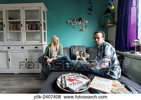 Tilburg, Netherlands. Young couple sitting in their living room, while being regular hosts for international travellers within the global Couch Surfing community. View Large Photo Image Stock Photo - Tilburg, Netherlands. Young couple sitting in their living room, while being regular hosts for international travellers within the global Couch Surfing community.. Fotosearch