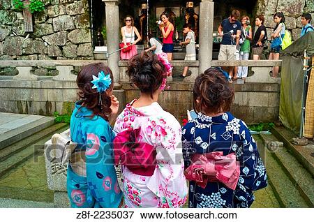 Stock Photo - Tourists try to collect falling water from the Otawa-no-taki waterfall with long metal cups at Kiyomizu-dera temple.. Fotosearch