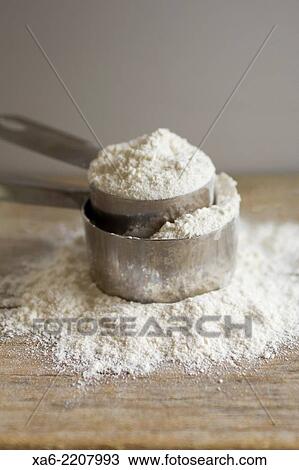 Two measuring cups full of flour sit on a wooden board. View Large Photo Image Stock Image - Two measuring cups full of flour sit on a wooden board.. Fotosearch