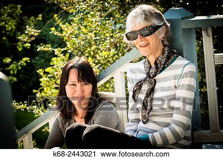 two women outdoors on a step with garden behind View Large Photo Image Stock Image - two women outdoors on a step with garden behind. Fotosearch
