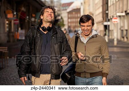 Two youn men laughing on street. View Large Photo Image Stock Image - Two youn men laughing on street.. Fotosearch