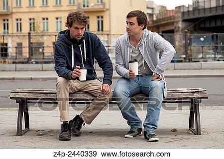 Two young people chat on a bench. View Large Photo Image Stock Photo - Two young people chat on a bench.. Fotosearch