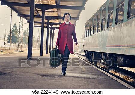 Woman carrying suitcase standing on railroad station platform, front view View Large Photo Image Stock Photo - Woman carrying suitcase standing on railroad station platform, front view. Fotosearch