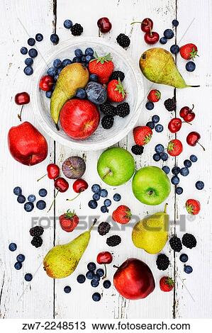 Stock Image - Wooden fruit bowl surrounded with fruit.. Fotosearch