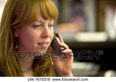 Young, attractive and redheaded woman, having a phone-conversation, while working in the museum bookstore. View Large Photo Image Stock Photograph - Young, attractive and redheaded woman, having a phone-conversation, while working in the museum bookstore.. Fotosearch