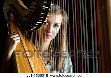 Stock Photograph - Young, female student at conservatoire playing harp at graduate level.. Fotosearch