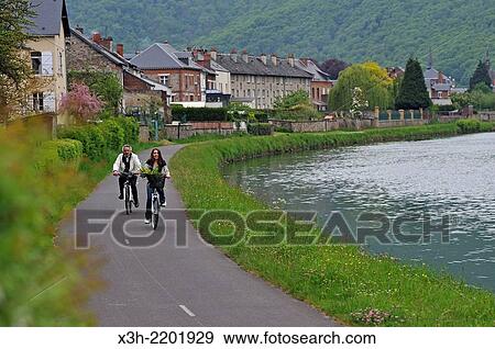 young woman and a man cycling on cycle lane along the Meuse River at Haybes, Ardennes department, Champagne-Ardenne region of northeasthern France, Europe. View Large Photo Image Stock Photo - young woman and a man cycling on cycle lane along the Meuse River at Haybes, Ardennes department, Champagne-Ardenne region of northeasthern France, Europe.. Fotosearch