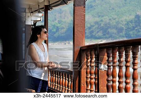 young woman standing at the railing of a cruise boat, owned by ´´ The Luang Say Lodge & Cruises´´, on Mekong River, between Pakbeng and Luang Prabang, Oudomxay Province, Laos, Southeast Asia. View Large Photo Image Stock Photo - young woman standing at the railing of a cruise boat, owned by ´´ The Luang Say Lodge & Cruises´´, on Mekong River, between Pakbeng and Luang Prabang, Oudomxay Province, Laos, Southeast Asia.. Fotosearch