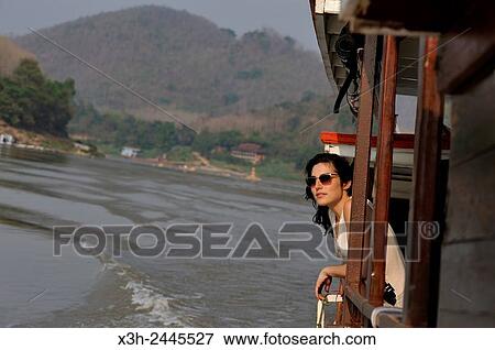 young woman standing at the railing of a cruise boat, owned by ´´ The Luang Say Lodge & Cruises´´, on Mekong River, between Pakbeng and Luang Prabang, Oudomxay Province, Laos, Southeast Asia. View Large Photo Image Stock Photo - young woman standing at the railing of a cruise boat, owned by ´´ The Luang Say Lodge & Cruises´´, on Mekong River, between Pakbeng and Luang Prabang, Oudomxay Province, Laos, Southeast Asia.. Fotosearch
