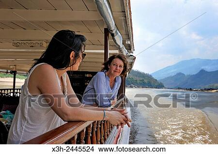 young women standing at the railing of a cruise boat, owned by ´´ The Luang Say Lodge & Cruises´´, on Mekong River, between Pakbeng and Luang Prabang, Oudomxay Province, Laos, Southeast Asia. View Large Photo Image Picture - young women standing at the railing of a cruise boat, owned by ´´ The Luang Say Lodge & Cruises´´, on Mekong River, between Pakbeng and Luang Prabang, Oudomxay Province, Laos, Southeast Asia.. Fotosearch