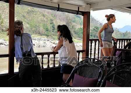young women standing at the railing of a cruise boat, owned by ´´ The Luang Say Lodge & Cruises´´, on Mekong River, between Pakbeng and Luang Prabang, Oudomxay Province, Laos, Southeast Asia. View Large Photo Image Stock Image - young women standing at the railing of a cruise boat, owned by ´´ The Luang Say Lodge & Cruises´´, on Mekong River, between Pakbeng and Luang Prabang, Oudomxay Province, Laos, Southeast Asia.. Fotosearch